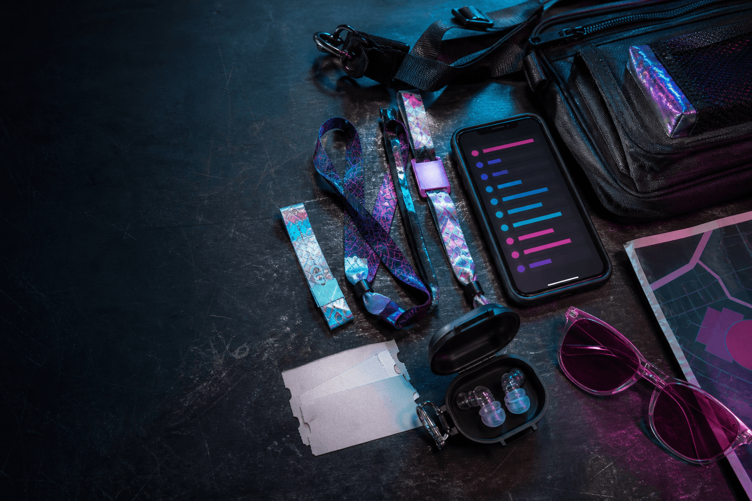 Festival wristbands, earplugs, tinted glasses, a crossbody bag, and a phone showing a color-coded lineup
